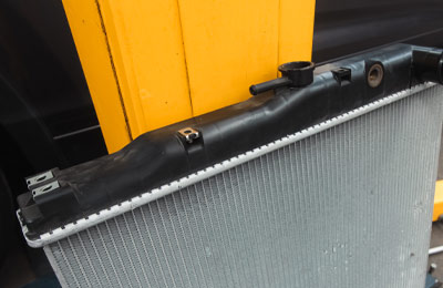 Close up photo of a new car radiator leaning against a yellow post