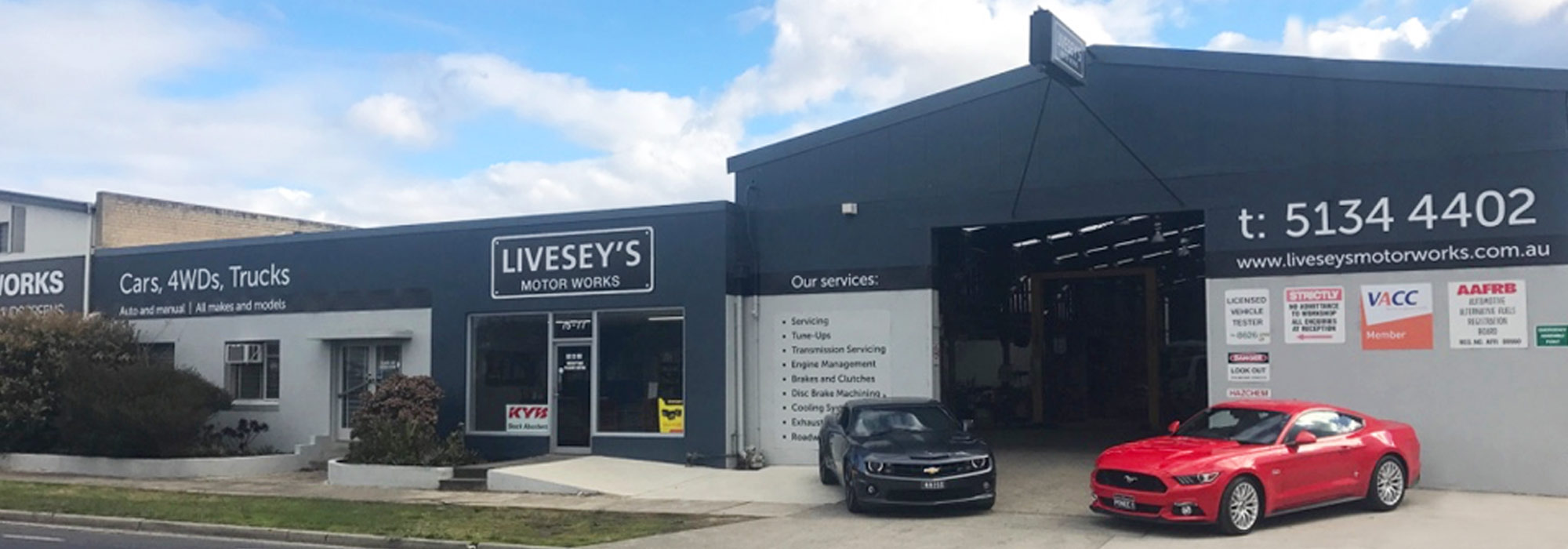 Photo of the front of the workshop for Livesseys Motor Works with two cars parked at the entry.